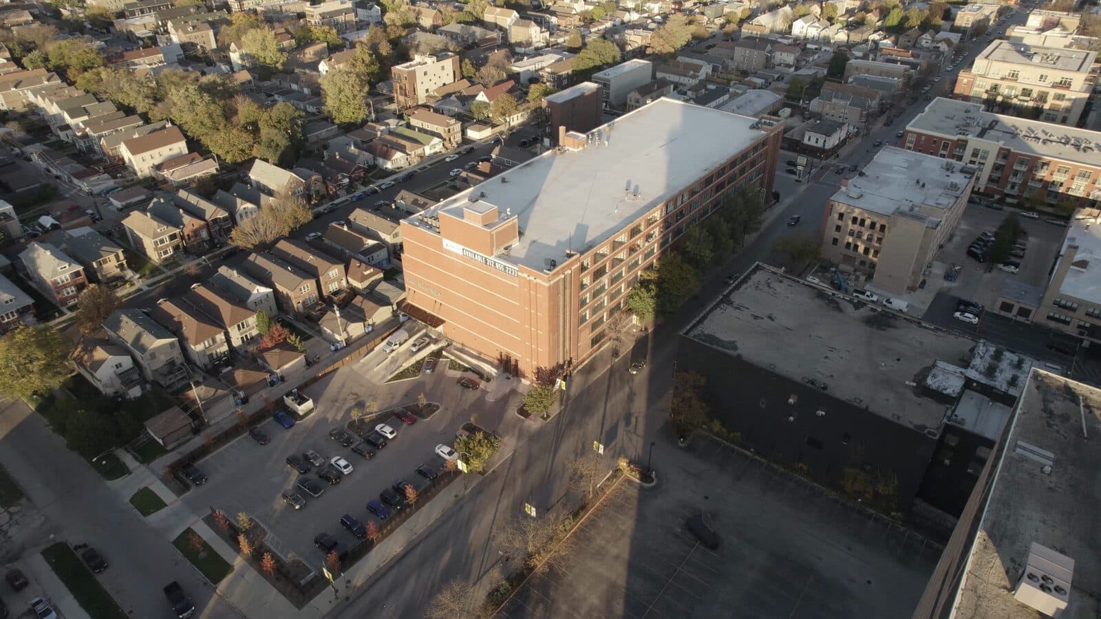 Aerial view at golden hour of the brick building in Bridgeport that the studio is in, with its parking lot